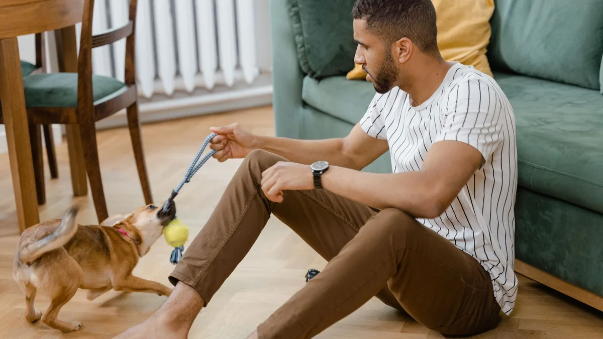Homme jouant au tir à la corde avec son chien sur un parquet